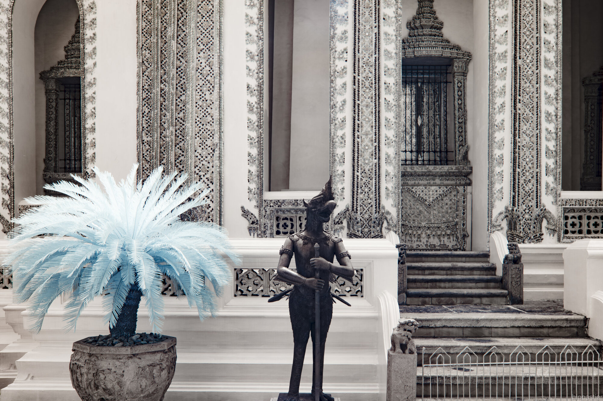Blue infrared palm frond beside a guardian statue at Wat Phra Kaew, Bangkok
